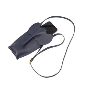 May include: A navy blue leather phone case shaped like an elephant with a long trunk and large ears. The case has a strap for carrying it over the shoulder.