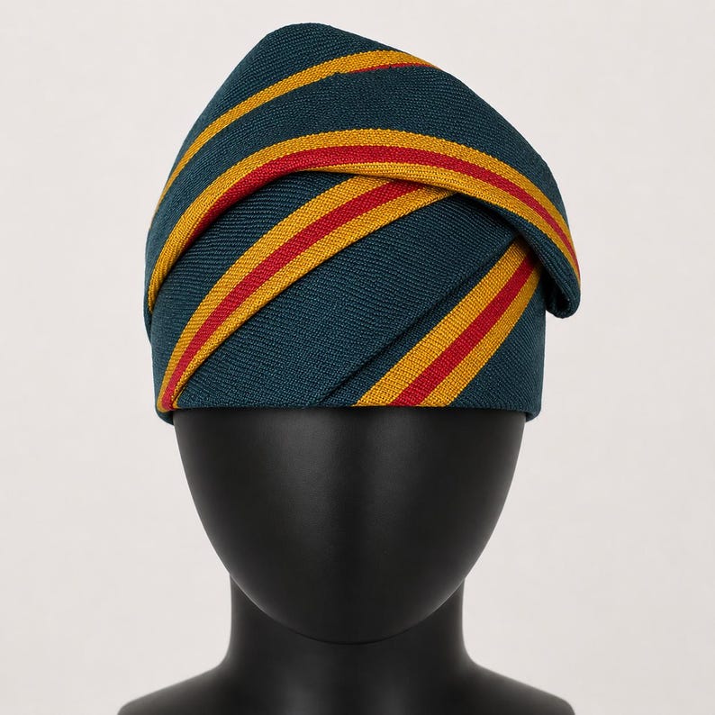 Peut inclure: Un chapeau de couleur sarcelle orn&eacute; de rayures horizontales rouges et dor&eacute;es. Le chapeau est pli&eacute; et enroul&eacute;, cr&eacute;ant une forme unique. Il est pr&eacute;sent&eacute; sur une t&ecirc;te de mannequin noire.