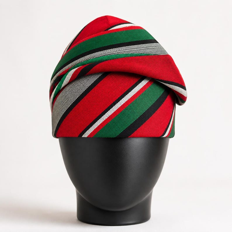 Peut inclure: Un turban ray&eacute; rouge, vert, noir et blanc. Le couvre-chef est pr&eacute;sent&eacute; sur une t&ecirc;te de mannequin noire sur fond blanc. Le tissu pr&eacute;sente un motif &agrave; rayures diagonales.