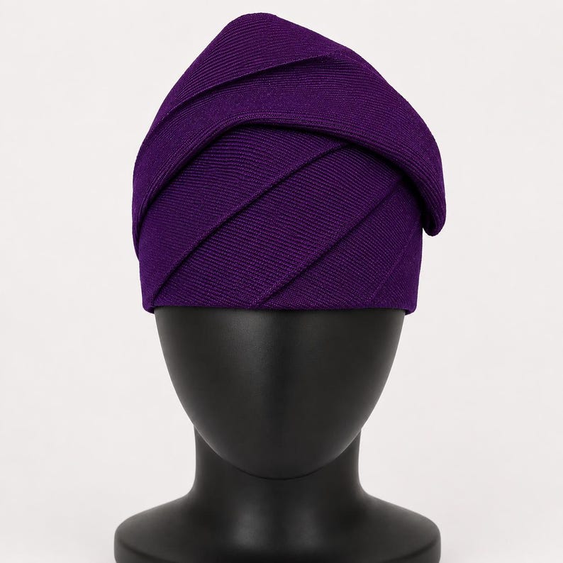 Peut inclure: Un chapeau violet fonc&eacute; avec un design superpos&eacute; unique. Le tissu du chapeau est c&ocirc;tel&eacute; et les couches cr&eacute;ent un aspect textur&eacute; et g&eacute;om&eacute;trique. Le chapeau est pr&eacute;sent&eacute; sur une t&ecirc;te de mannequin noire, mettant en valeur sa forme et son style.