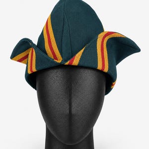 May include: A teal-colored hat with yellow and red stripes. The hat is displayed on a black mannequin head. The hat has a unique shape with pointed top and folded edges. The stripes run vertically along the hat's surface.