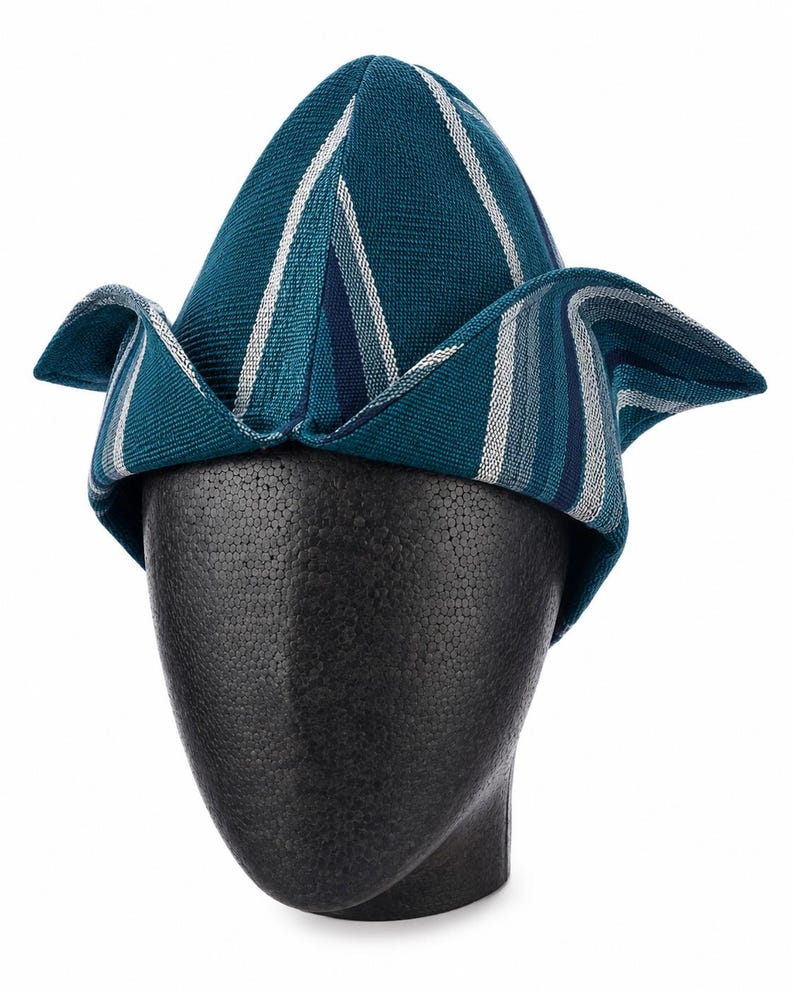 May include: Teal and white striped hat with a unique folded brim design. The hat is displayed on a black mannequin head. The hat's fabric has a textured appearance, and the stripes run vertically and diagonally across the crown and brim.