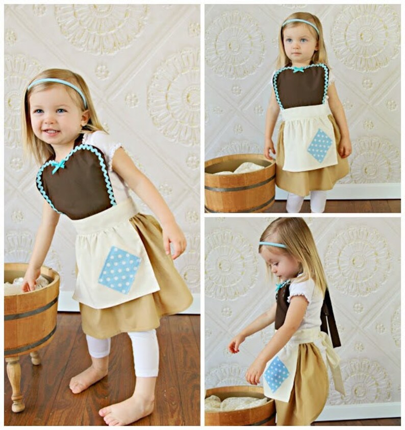 May include: A child's costume featuring a brown bib with a blue bow and trim, paired with a tan skirt and white apron with a blue polka dot patch. The outfit includes a matching blue headband. The costume is designed for a young child.