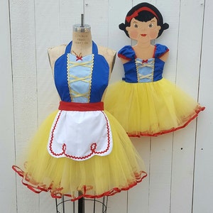 May include: A Snow White costume set with a blue and yellow bodice and a yellow tulle skirt. The set includes a matching apron with a white bib and red trim.