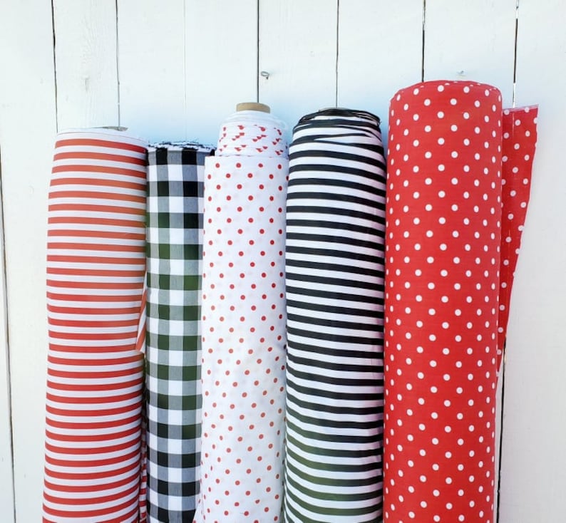May include: Five rolls of fabric with different patterns. The fabric rolls are red and white striped, black and white checkered, red with white polka dots, black and white striped, and red with white polka dots.