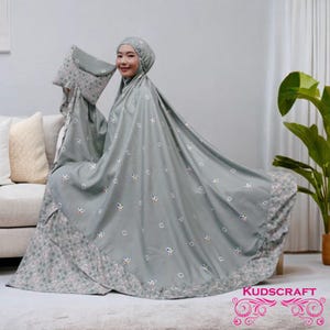 May include: A grey prayer shawl with a floral pattern around the edges and small white circles with colourful accents throughout. The shawl is folded and draped over a couch. The text "KUDSCRAFT" is visible in the bottom right corner of the image.