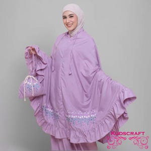 May include: A lavender prayer shawl with a ruffled hem and floral embroidery. It has a matching drawstring bag with a floral design.