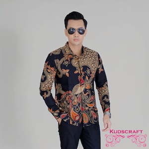Op de afbeelding: Een marineblauw overhemd met lange mouwen en een pauwontwerp in goud, oranje en rood. Het overhemd heeft een klassieke kraag en manchetten. De merknaam "KUDSCRAFT" is zichtbaar.