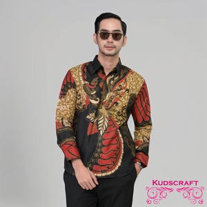 May include: A black long-sleeved shirt with a red, gold, and black batik pattern. The shirt has a button-up collar and a KUDSCRAFT logo on the bottom right corner.