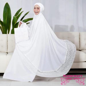 May include: White prayer shawl with lace trim. The shawl is draped over a white sofa. The word "KUDSCRAFT" is printed on the bottom right corner of the image.