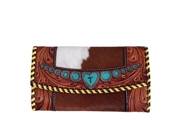 May include: Brown leather wallet with a white and brown cowhide pattern. The wallet has a turquoise and silver heart design with a cross in the center. The wallet has a yellow stitching detail around the edges.