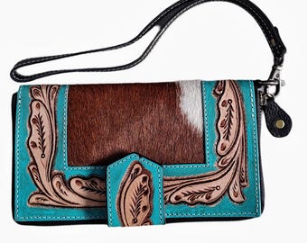 May include: A brown and white cowhide leather wallet with turquoise and brown leather accents. The wallet has a flap closure and a detachable strap.