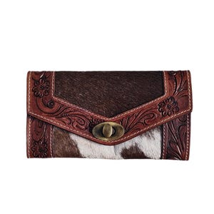 Puede incluir: Una cartera de cuero de vaca marr&oacute;n y blanco con un dise&ntilde;o floral tallado y un cierre de lat&oacute;n.