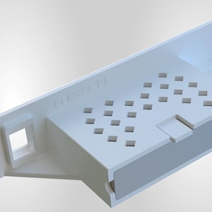 Può includere: Un componente elettronico bianco e rettangolare con una serie di ritagli quadrati e un'apertura rettangolare. Il componente ha una sezione lunga e piatta con due fori e il testo "Matrix 10".