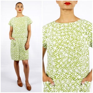 Könnte beinhalten: Ein kurzärmliges Kleid mit grünem und weißem Blumenmuster, Rundhalsausschnitt und zwei Taschen.