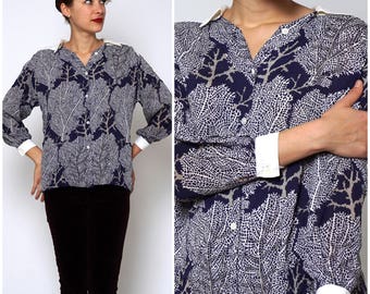 May include: A long-sleeved button-up shirt with a white collar and cuffs. The shirt is navy blue with a white floral pattern.