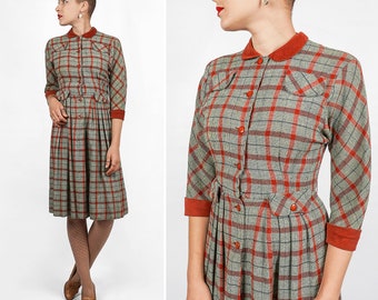 May include: A red and gray plaid dress with a collared neckline, long sleeves, and a button-up front. The dress has a fitted bodice and a full skirt.