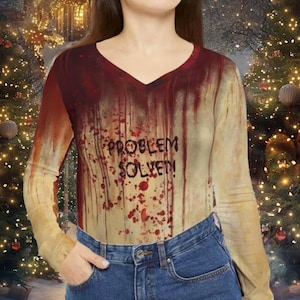 May include: A long-sleeved shirt with a beige background and red splatters. The shirt has a v-neck and the text "Problem Solved!" in red.