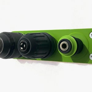 Op de afbeelding: Groene wandbevestiging met twee zwarte boorchucken en een groene CENTROTEC snelwisselchuck. De wandbevestiging heeft aan elke kant twee zilveren schroeven.