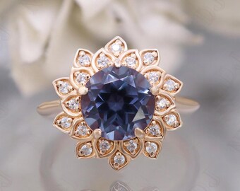 May include: A rose gold engagement ring with a large, round, dark blue gemstone surrounded by a halo of smaller, round, white gemstones.