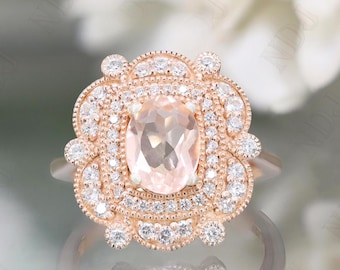 May include: A rose gold ring featuring a large, oval-cut peach-colored gemstone at the center, surrounded by a halo of small, sparkling white diamonds. The ring has an ornate, floral-inspired design.
