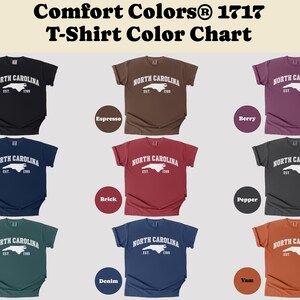 May include: A color chart of Comfort Colors 1717 t-shirts. The chart displays various t-shirt colors, including black, espresso, berry, true navy, brick, pepper, blue spruce, denim, and yam. Each shirt features a white graphic of the North Carolina outline.