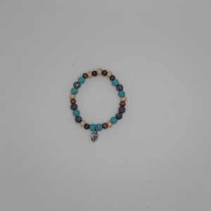 May include: A turquoise, brown, and beige beaded bracelet with a silver heart charm.