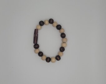 Puede incluir: Un brazalete de cuentas de madera con cuentas de color marrón y crema alternas. El brazalete tiene un cierre de madera marrón.