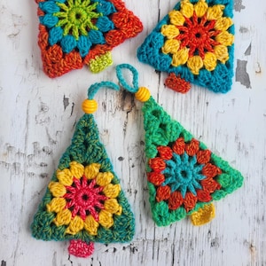 Può includere: Una collezione di ornamenti natalizi all'uncinetto fatti a mano. Ogni albero presenta un vivace disegno floreale al centro, con colori come rosso, giallo, blu e verde. Gli ornamenti hanno un anello per appenderli e una piccola perla gialla.