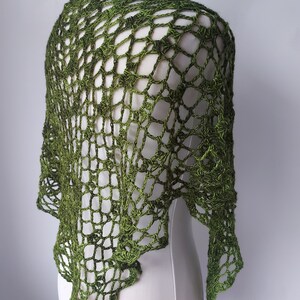 May include: A green crochet shawl with a delicate openwork pattern. The shawl is draped over a white dress form.