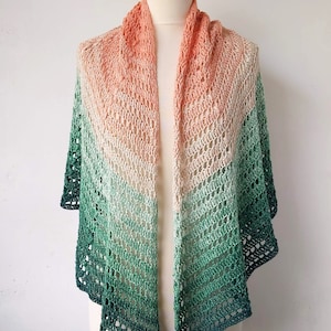 May include: A crocheted shawl with a gradient of peach, cream, and green colors. The shawl is made with a delicate openwork stitch.