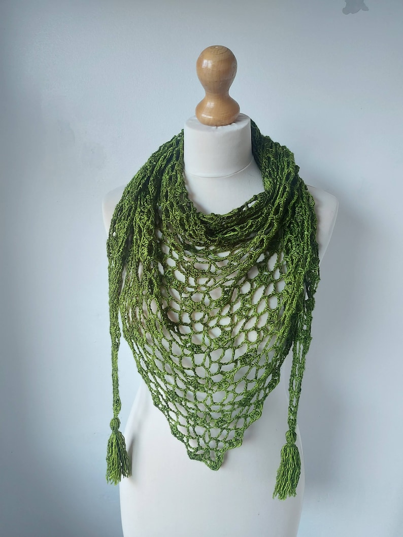 May include: A green crocheted shawl with a triangular shape and tassels on the ends.