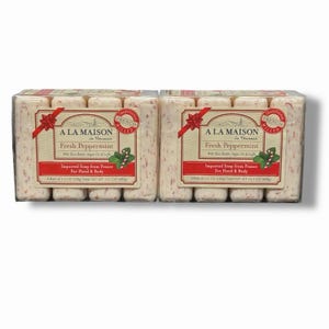 May include: Two packages of A La Maison Fresh Peppermint soap. Each package contains four bars of soap. The soap bars are white with red specks. The packaging includes a red ribbon and a label with the brand name and product information.