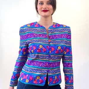 May include: A purple, blue, green, pink, and yellow striped blazer with a floral pattern. The blazer has a button closure and long sleeves.