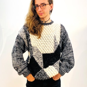 Pode incluir: Um suéter de gola redonda com um padrão geométrico preto, branco e cinza.