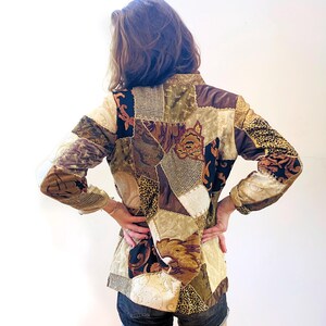 Op de afbeelding: Een bruin, beige en zwart patchworkjack met lange mouwen. Het jack is gemaakt van verschillende stoffen en patronen, waaronder bloemen, geometrische en dierenprint.
