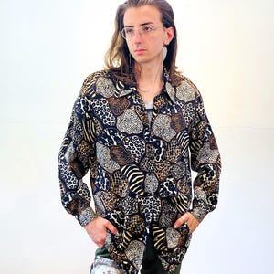 May include: A long-sleeved button-up shirt with a black background and a colorful patchwork pattern of animal prints, including leopard, zebra, and cheetah.