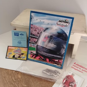 May include: A selection of Daytona 500 memorabilia, including a souvenir programme featuring a racing helmet with an American flag design. Also included are event tickets and a promotional booklet.