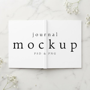 Puede incluir: Un diario abierto de color blanco con texto negro centrado en las páginas. El texto dice journal, mockup y PSD & PNG. El diario se muestra plano, revelando dos páginas blancas en blanco con un lomo central que divide el diseño.