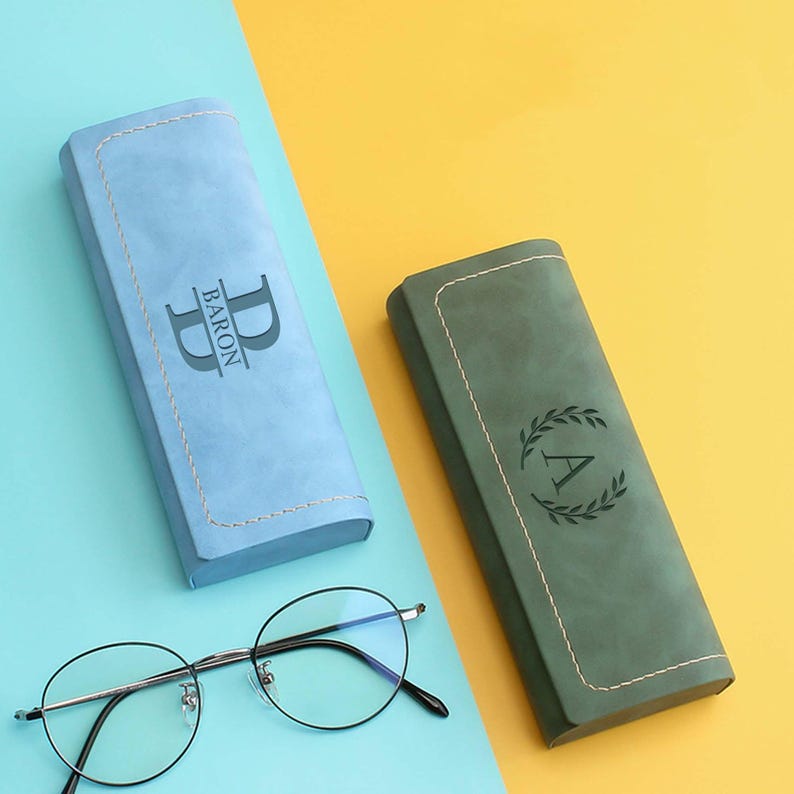 Peut inclure: Deux &eacute;tuis &agrave; lunettes personnalis&eacute;s, un bleu clair avec les initiales "D.B." et le nom "BARON" et un vert fonc&eacute; avec une couronne et l'initiale "A".