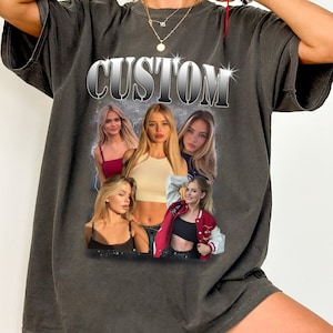 May include: A dark gray oversized t-shirt with the word "CUSTOM" printed in silver letters. The shirt features a collage of four women's faces.