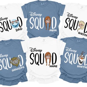K&ouml;nnte beinhalten: Sechs kurz&auml;rmelige T-Shirts in Wei&szlig; und Blau mit dem Text "Disney Squad" und Charaktergrafiken. Zu den Etiketten geh&ouml;ren "Dad", "Mom" und "Sister". Die Shirts sind aus einem weichen Material.