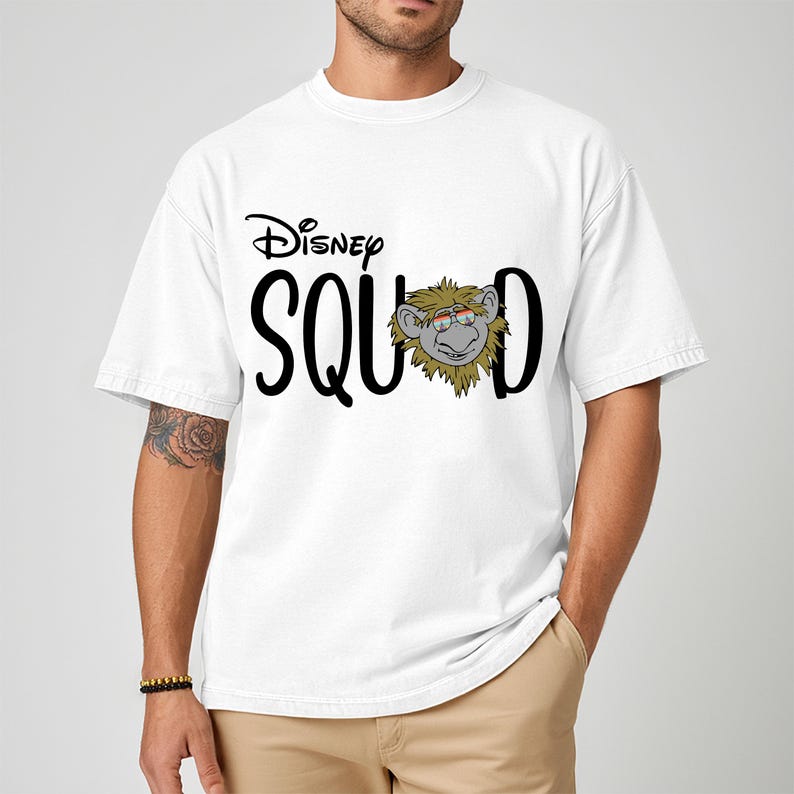 K&ouml;nnte beinhalten: Wei&szlig;es T-Shirt mit dem Text "Disney SQUAD" in schwarzer Schrift. Das "O" in SQUAD wird durch einen Cartoon-Affen mit Brille ersetzt. Das Disney-Logo befindet sich &uuml;ber dem Wort SQUAD.
