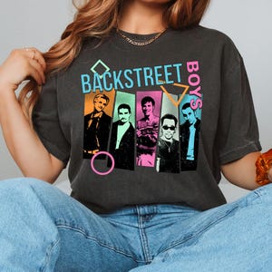 May include: Dark gray t-shirt featuring the text "BACKSTREET BOYS" in a colorful, retro design. The graphic includes images of the band members in individual panels. The shirt is a vintage style.