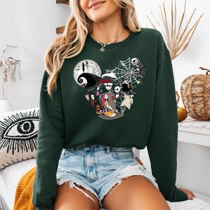 Puede incluir: Sudadera verde oscuro con un dise&ntilde;o de personajes de Pesadilla antes de Navidad. El dise&ntilde;o incluye a Jack Skellington, Sally y otros personajes, con una luna llena y telara&ntilde;as. Una c&oacute;moda parte superior de manga larga.