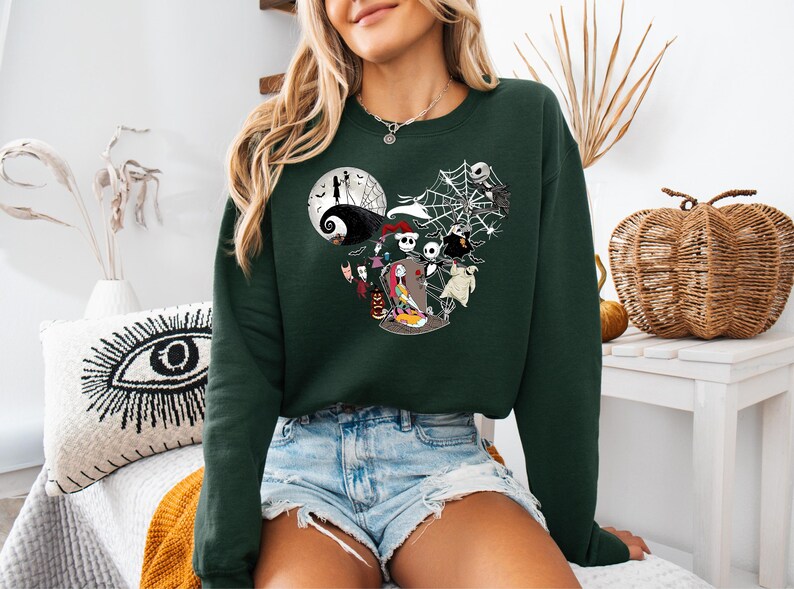 Puede incluir: Sudadera verde oscuro con un dise&ntilde;o de personajes de Pesadilla antes de Navidad. El dise&ntilde;o incluye a Jack Skellington, Sally y otros personajes, con una luna llena y telara&ntilde;as. Una c&oacute;moda parte superior de manga larga.
