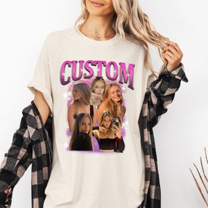 May include: A cream-colored t-shirt featuring the word CUSTOM in large pink letters with a black outline. Below the text is a collage of five photographs of a person with long blonde hair, set against a purple background with white star accents.