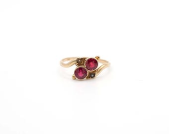 May include: A gold ring with two red gemstones and two small white pearls.