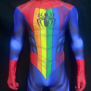 Puede incluir: Un traje de spandex azul y rojo con un diseño de arcoíris y un logotipo de araña negro en el pecho. El traje tiene cuello alto y mangas largas.