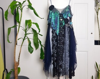 May include: A blue and green sequined top with black lace trim and a blue and black layered skirt. The top has a scalloped neckline and a floral design.